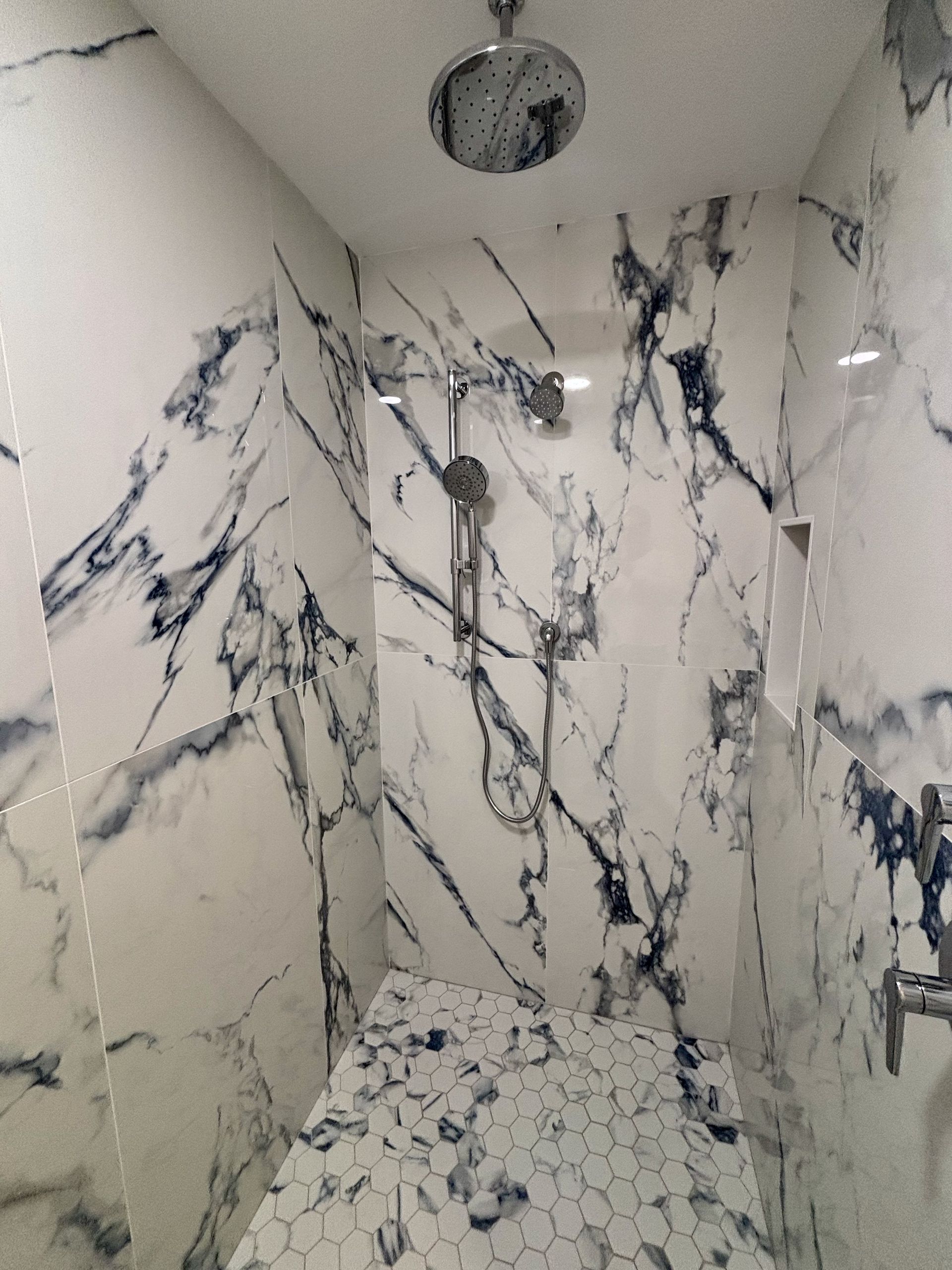 A bathroom with marble walls and a shower head