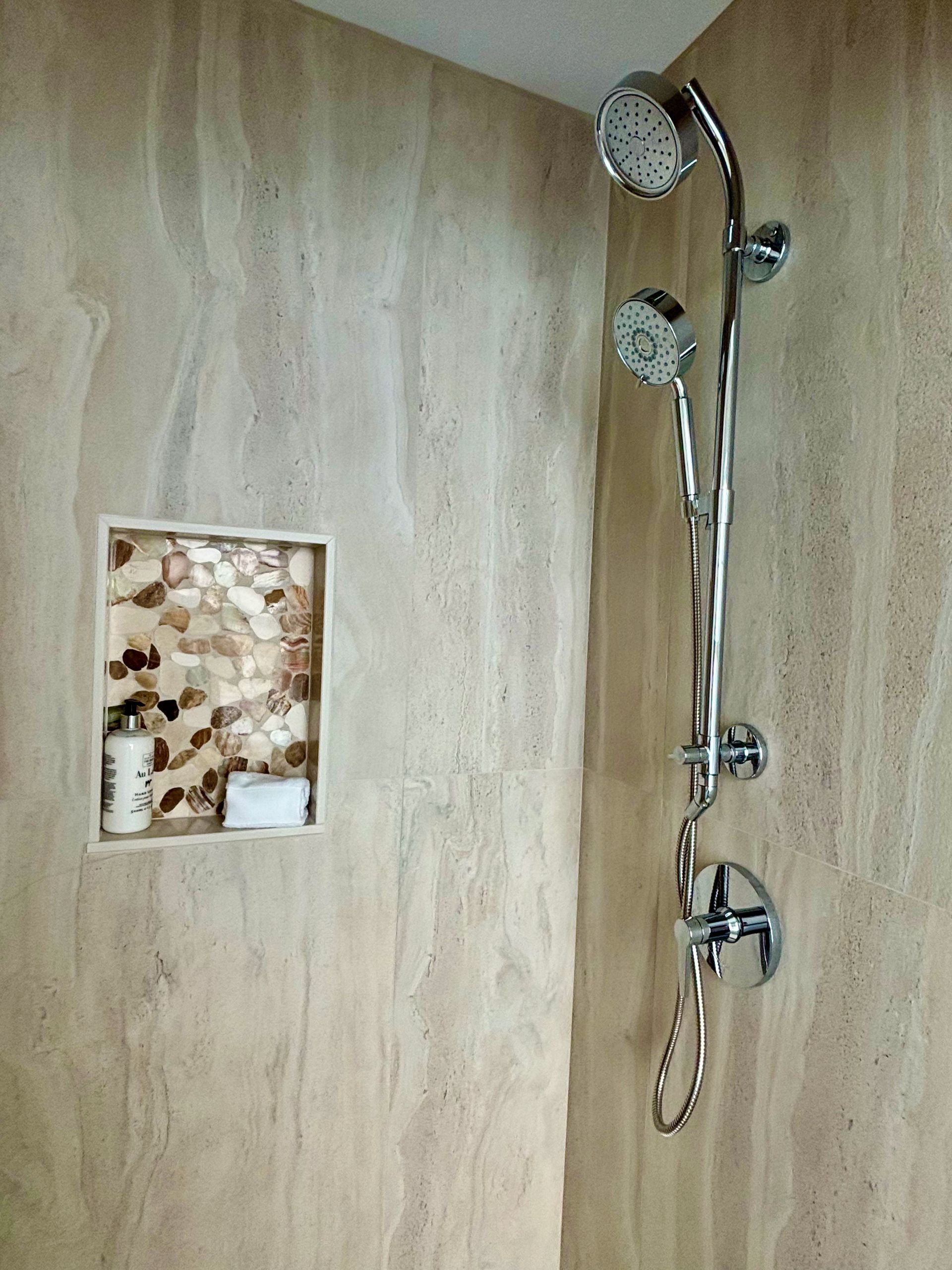 A shower with three shower heads and a soap dish