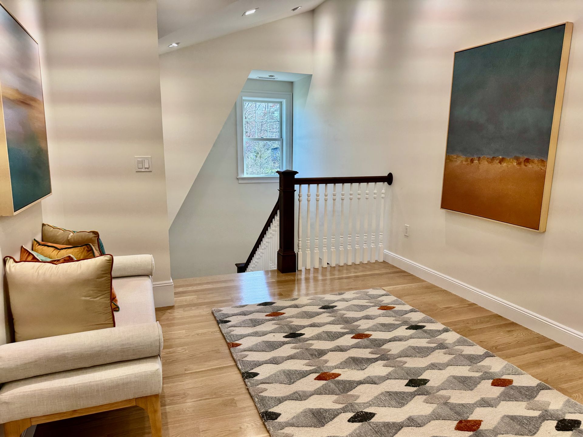 A living room with a rug , couch , and paintings on the wall.
