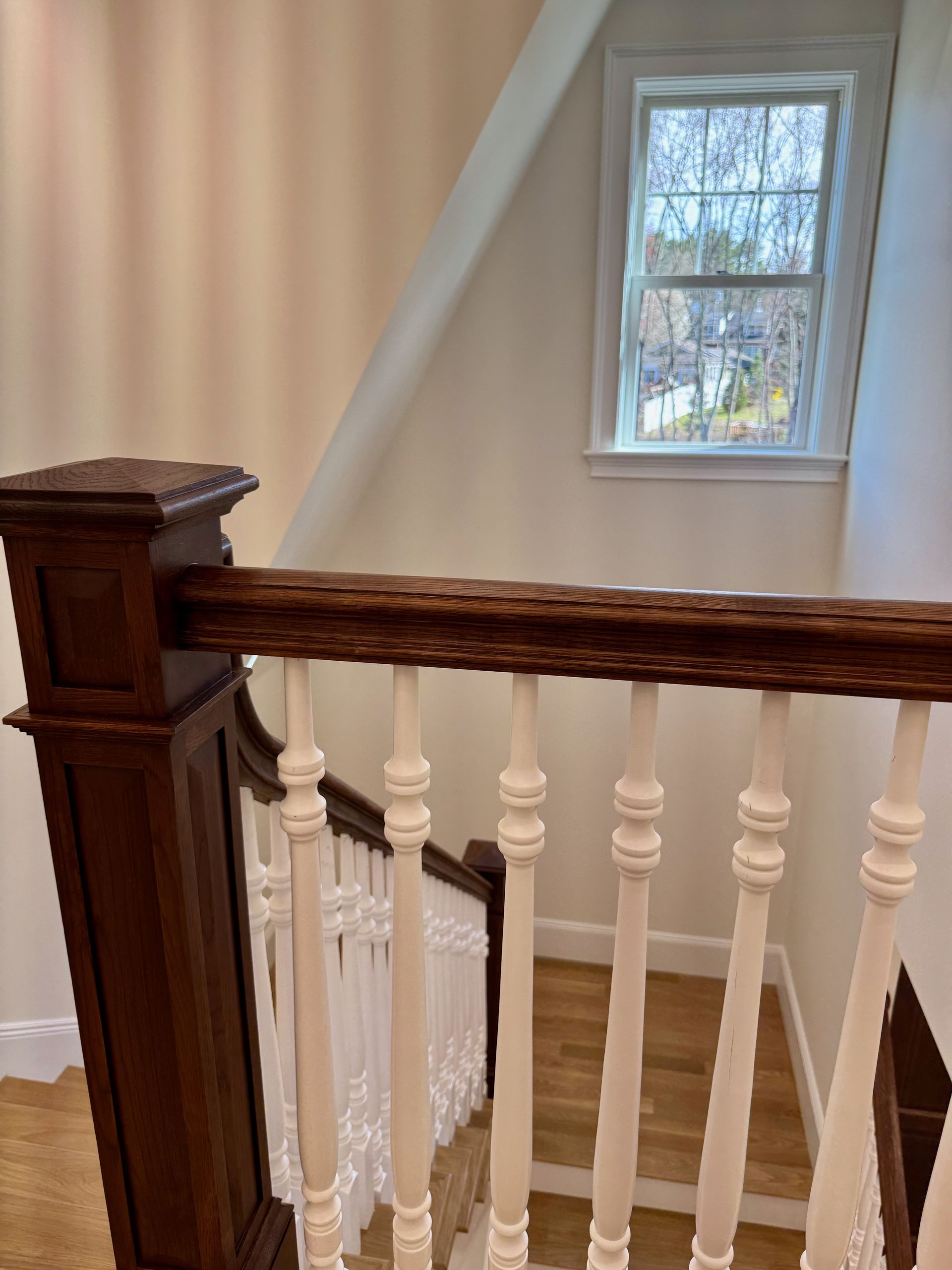 A staircase with a wooden railing and a window.