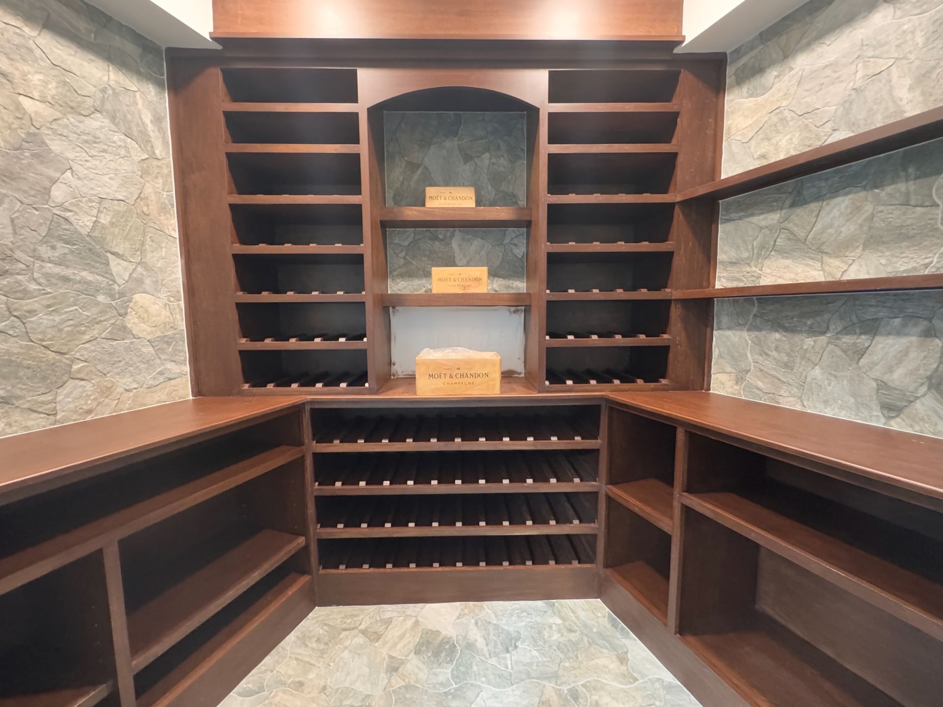 A wine cellar with lots of shelves and a box on top
