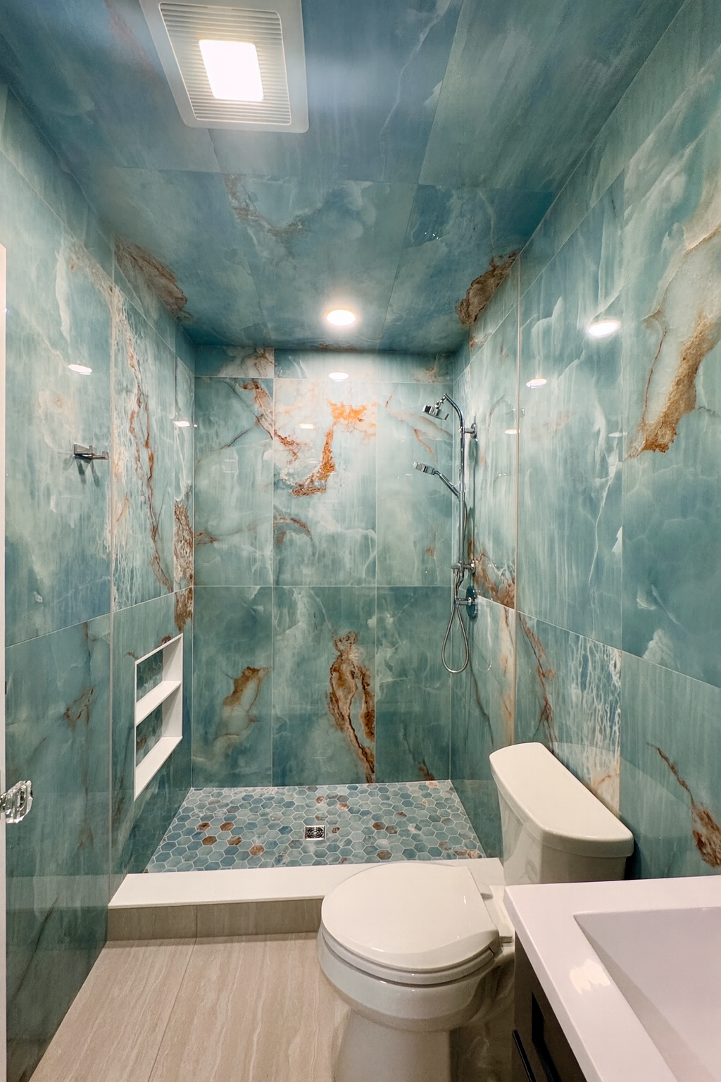 A bathroom with a toilet , sink and shower.