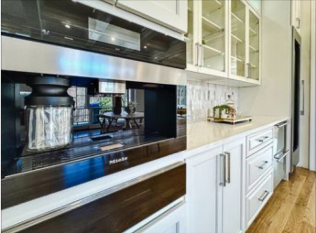 A kitchen with white cabinets and a stainless steel coffee maker.