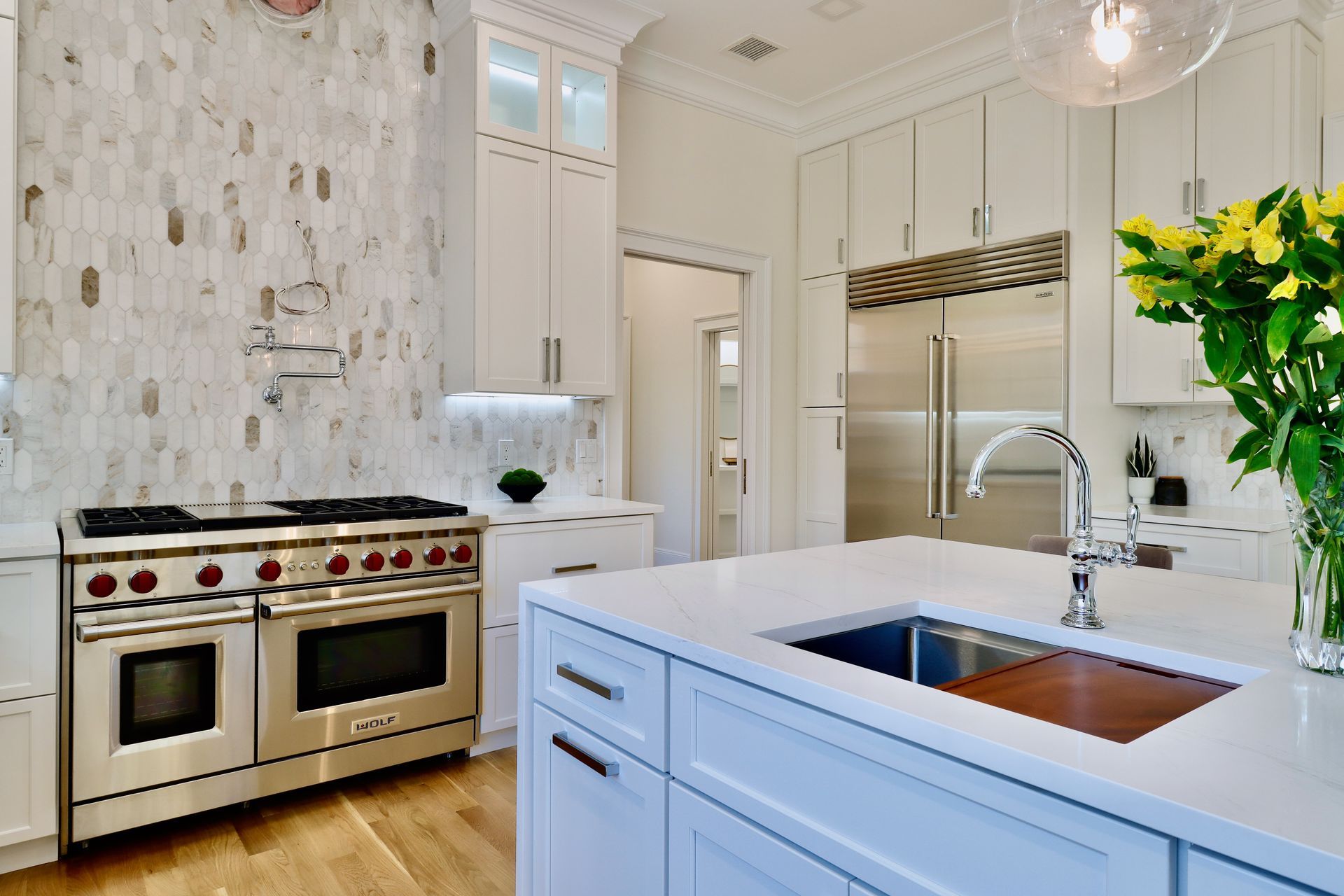 A kitchen with white cabinets , stainless steel appliances , a sink and a stove.