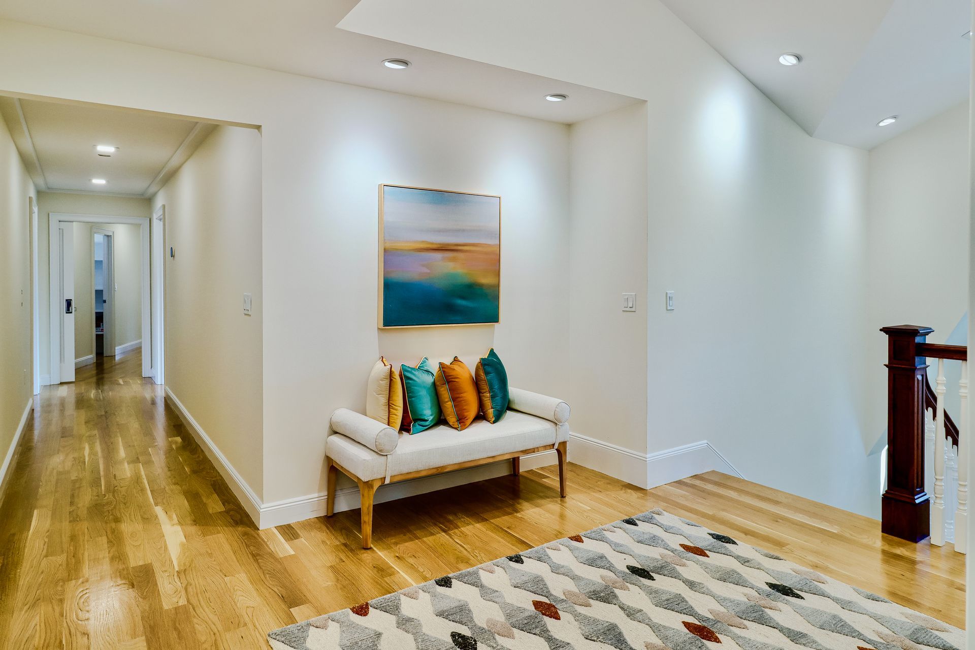 A hallway with a bench and a painting on the wall.