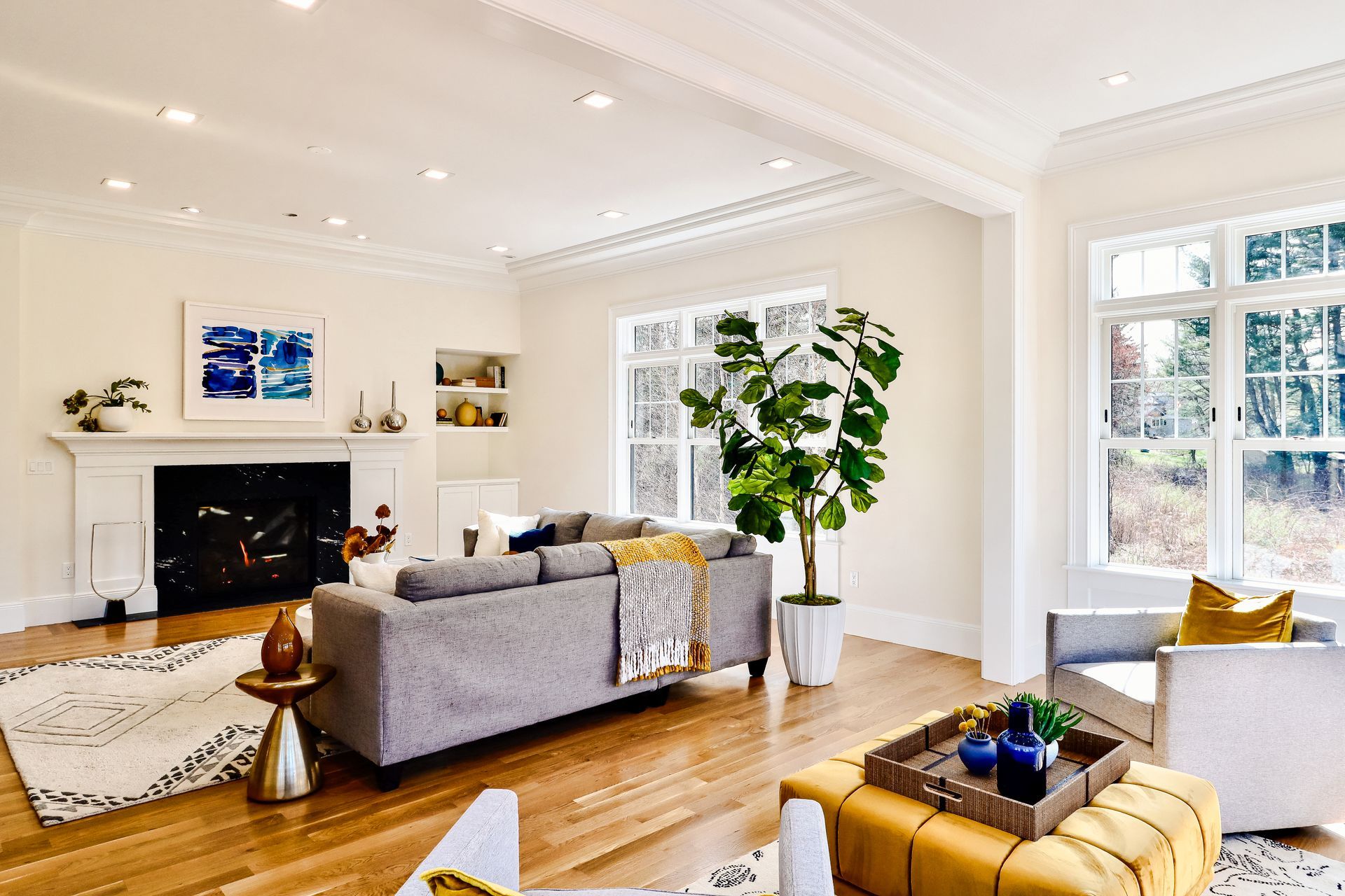 A living room with a couch , chairs , ottoman and fireplace.