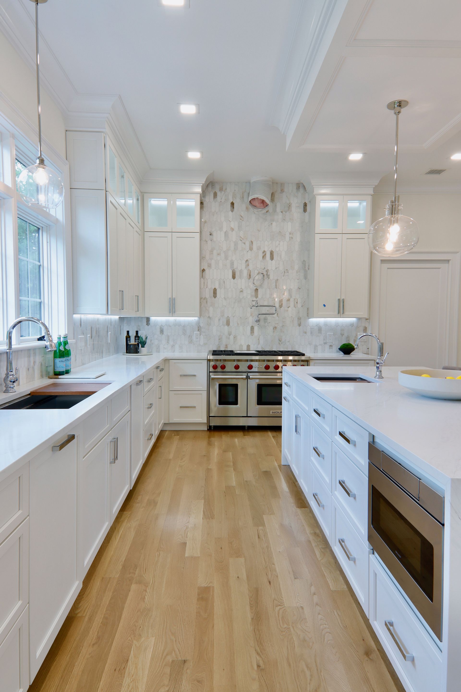 A kitchen with white cabinets , hardwood floors , and stainless steel appliances.
