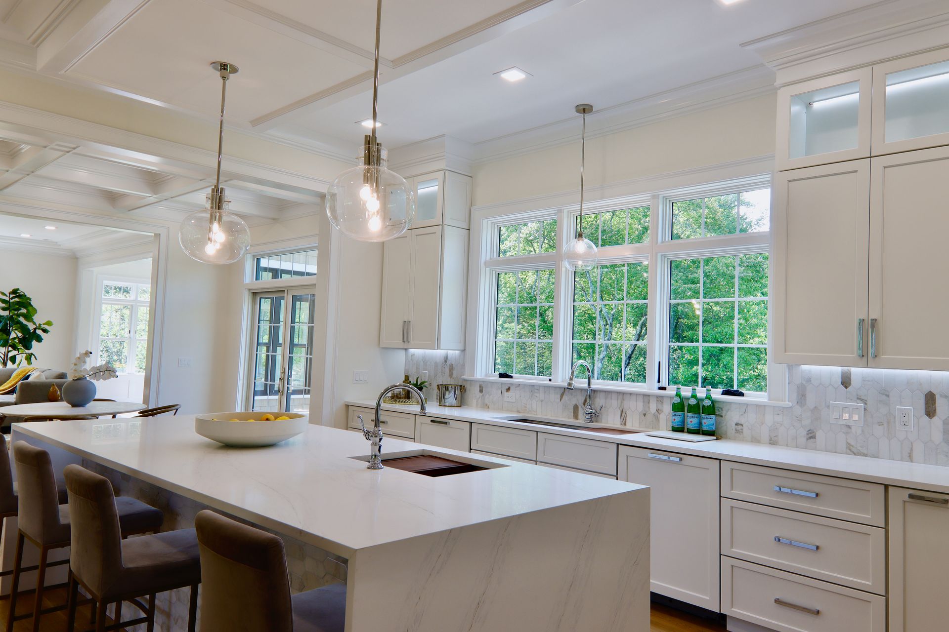 A kitchen with white cabinets , white counter tops , and a large island.