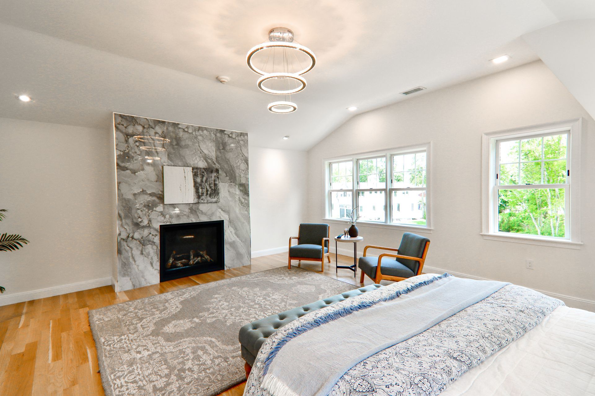 A bedroom with a bed , chairs , a fireplace and a rug.