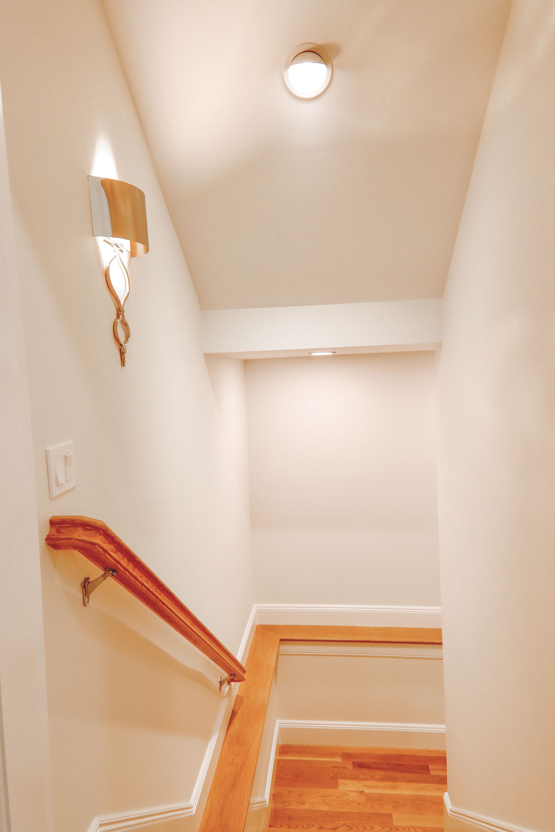 A staircase with a wooden handrail and a light on the ceiling.