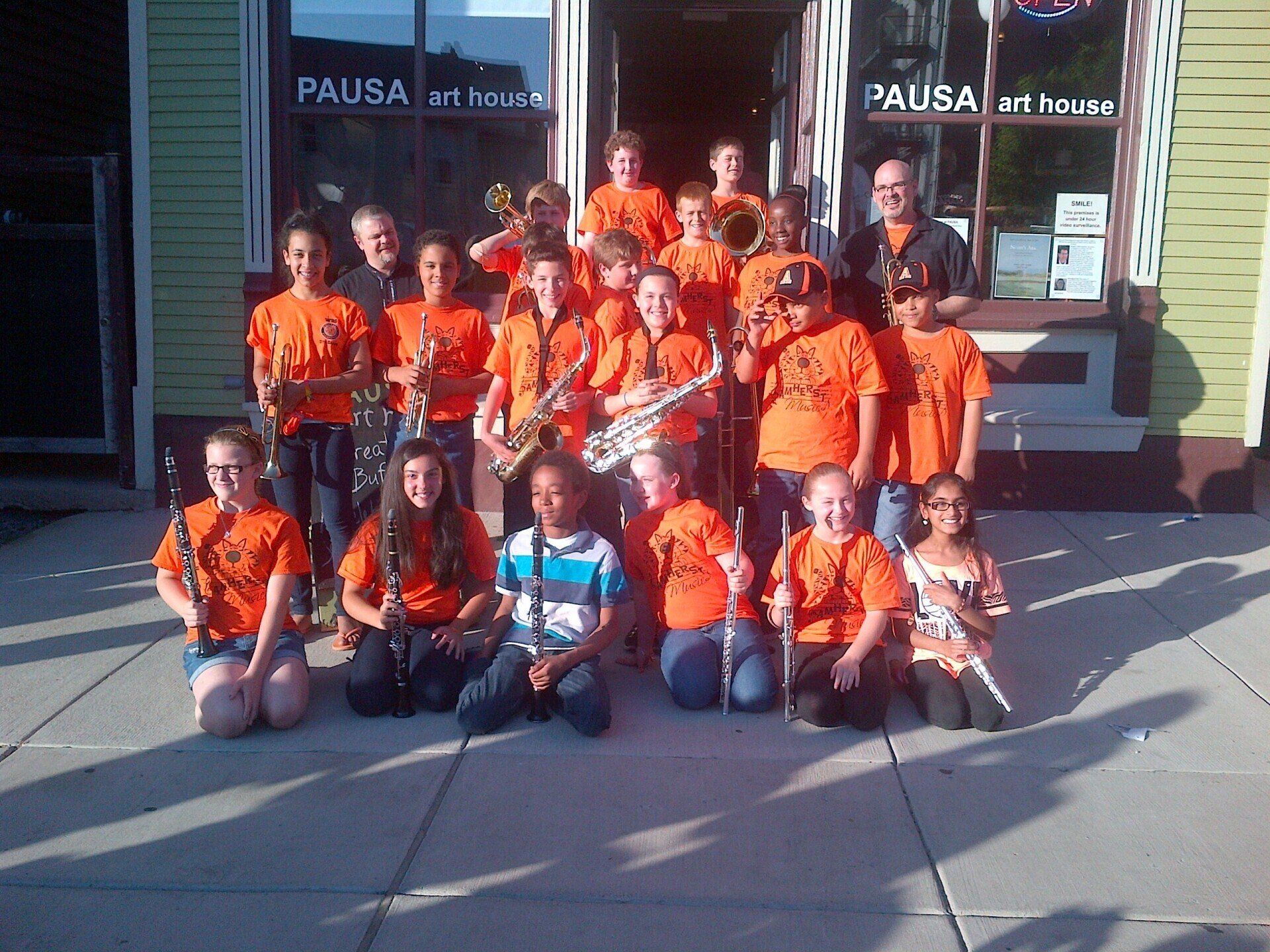 A group of kids are posing for a picture in front of a store called pausa