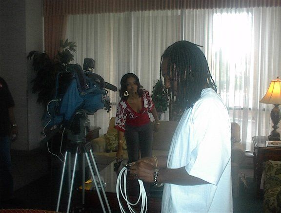 A man in a white shirt is standing in front of a camera in a living room.