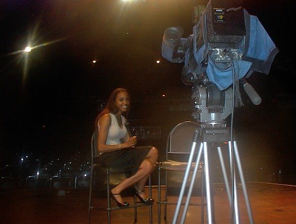 A woman sits in front of a camera on a tripod