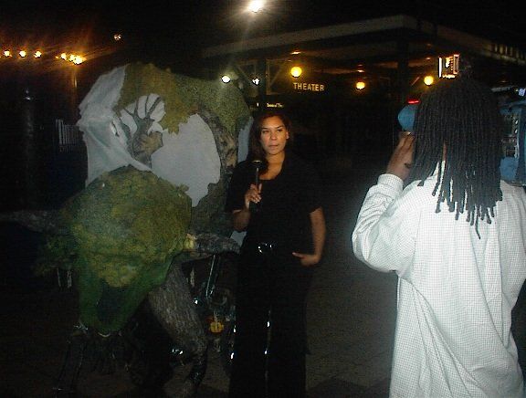 A man with dreadlocks is taking a picture of a woman