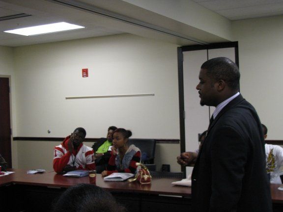 A man in a suit stands in front of a group of people