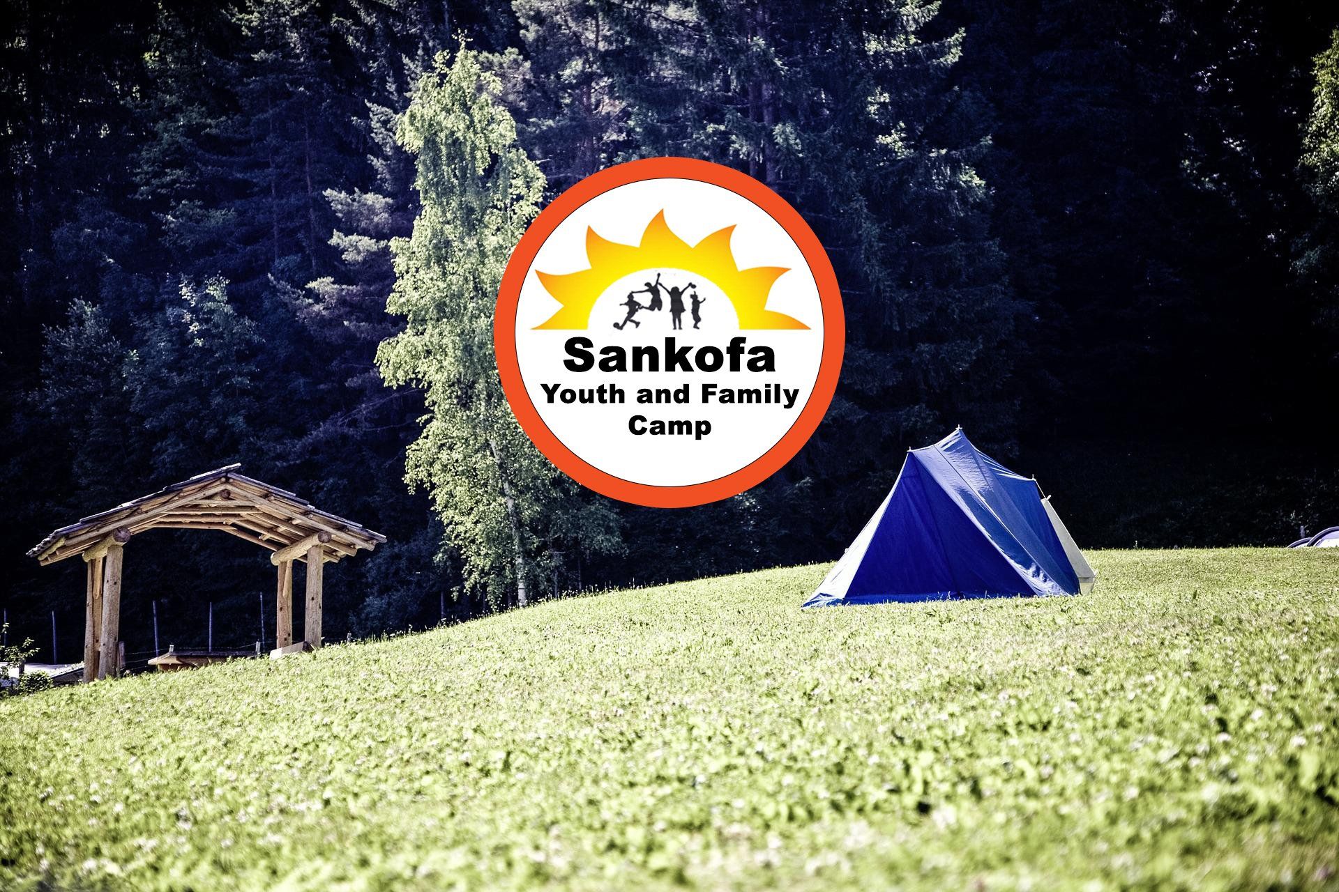 A blue tent in a grassy field with a sankota youth and family camp logo