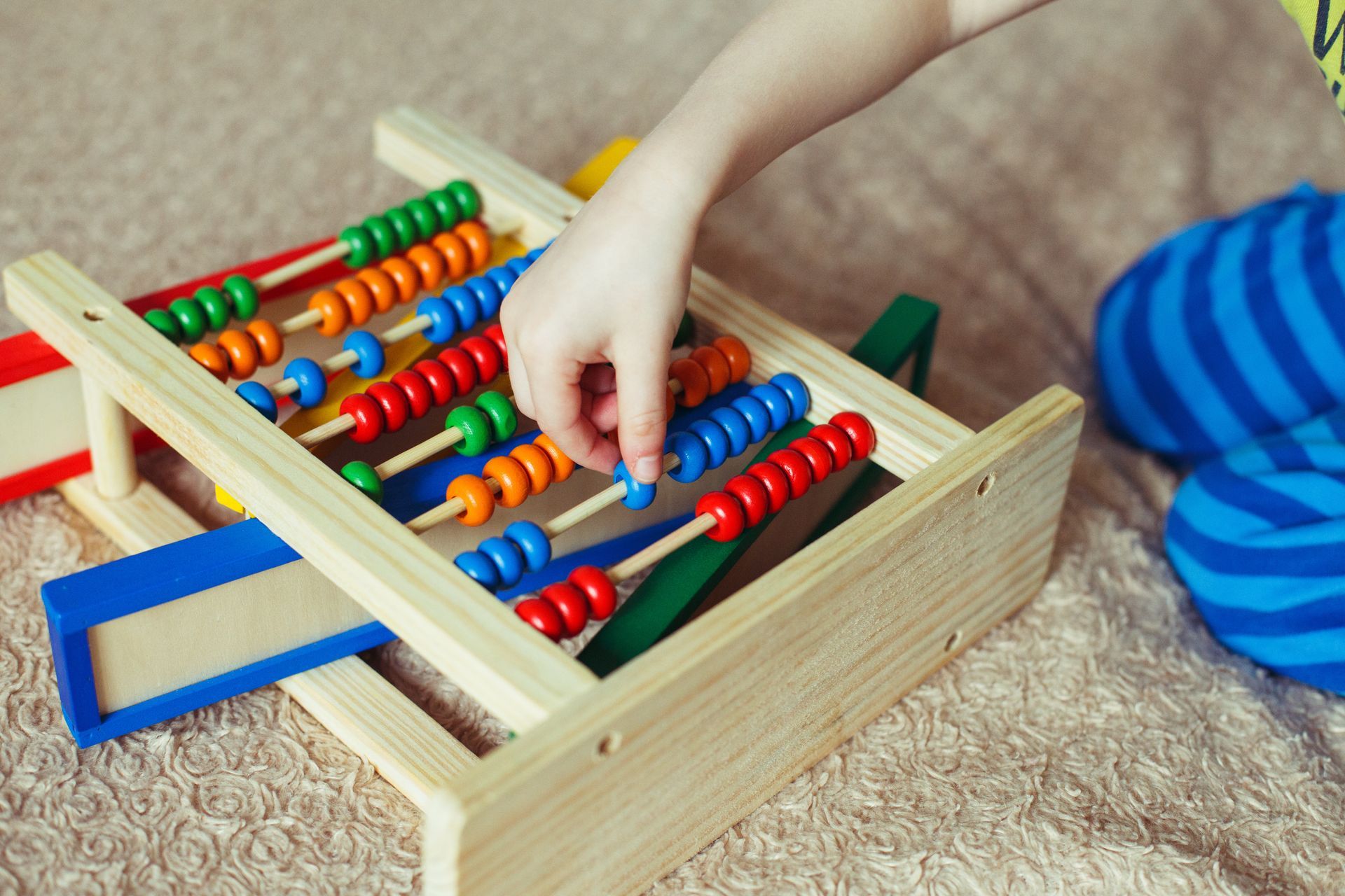 A partial view of a preschooler in pyjamas learning to count with an abacus toy on a bed. A partial view of a preschooler in pyjamas learning to count with an abacus toy on a bed.