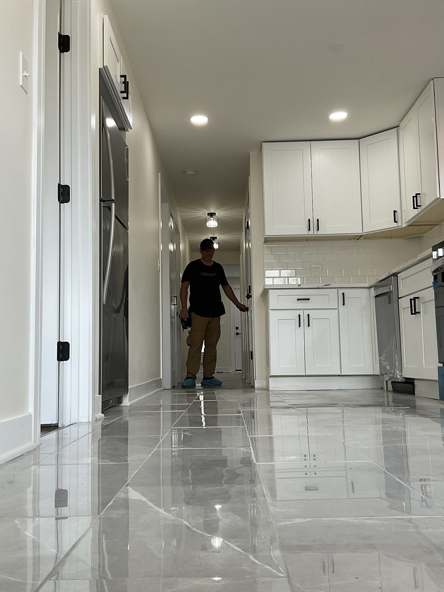 A man is walking down a hallway in a kitchen.