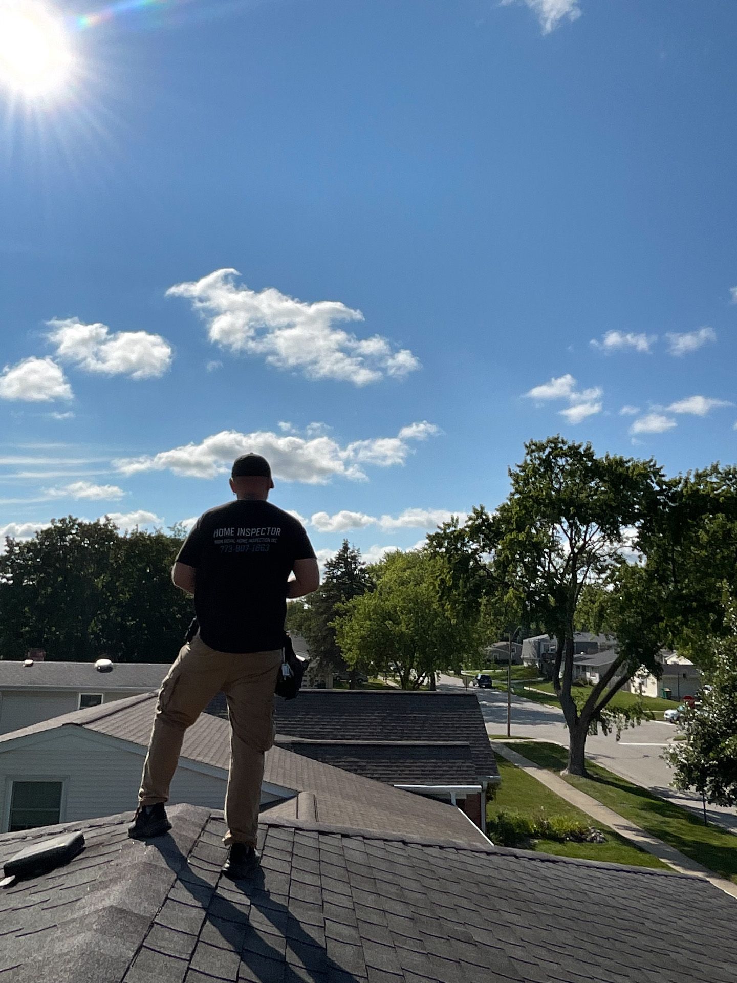 A man is standing on top of a roof looking at the sky.