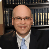 A man in a white shirt and tie is smiling