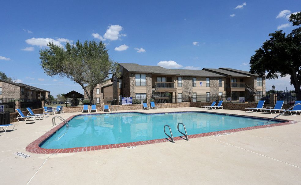 Outdoor apartment pool with blue lounge chairs and brick coping.