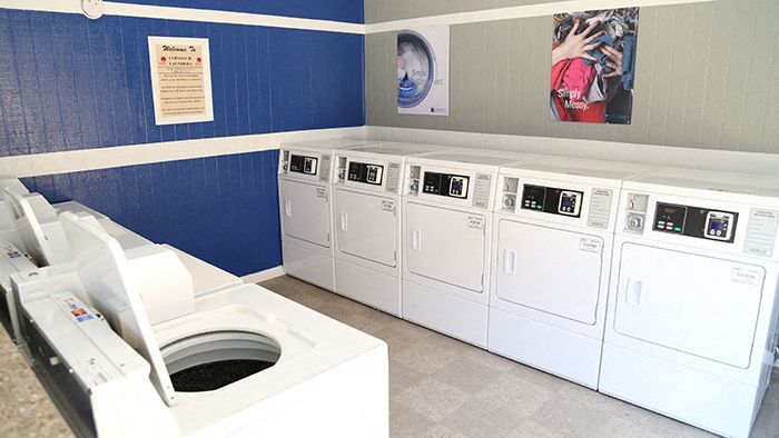 Community laundry room with a row of front-loading washers and dryers.