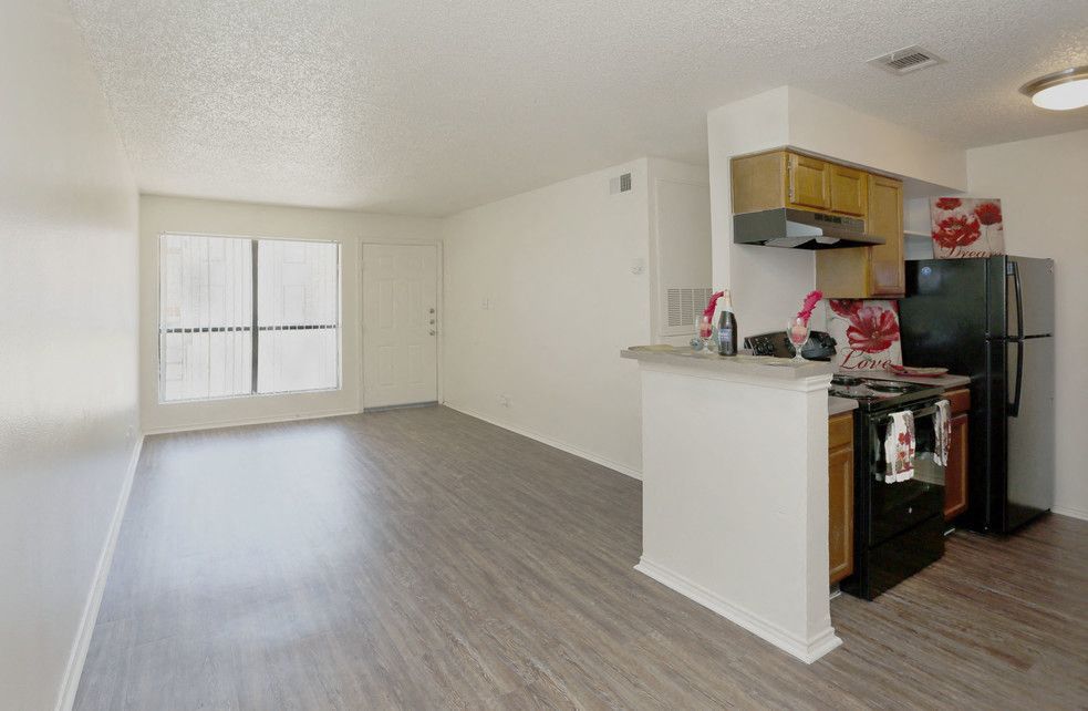 Open-concept living room and kitchen in a white apartment with laminate flooring.