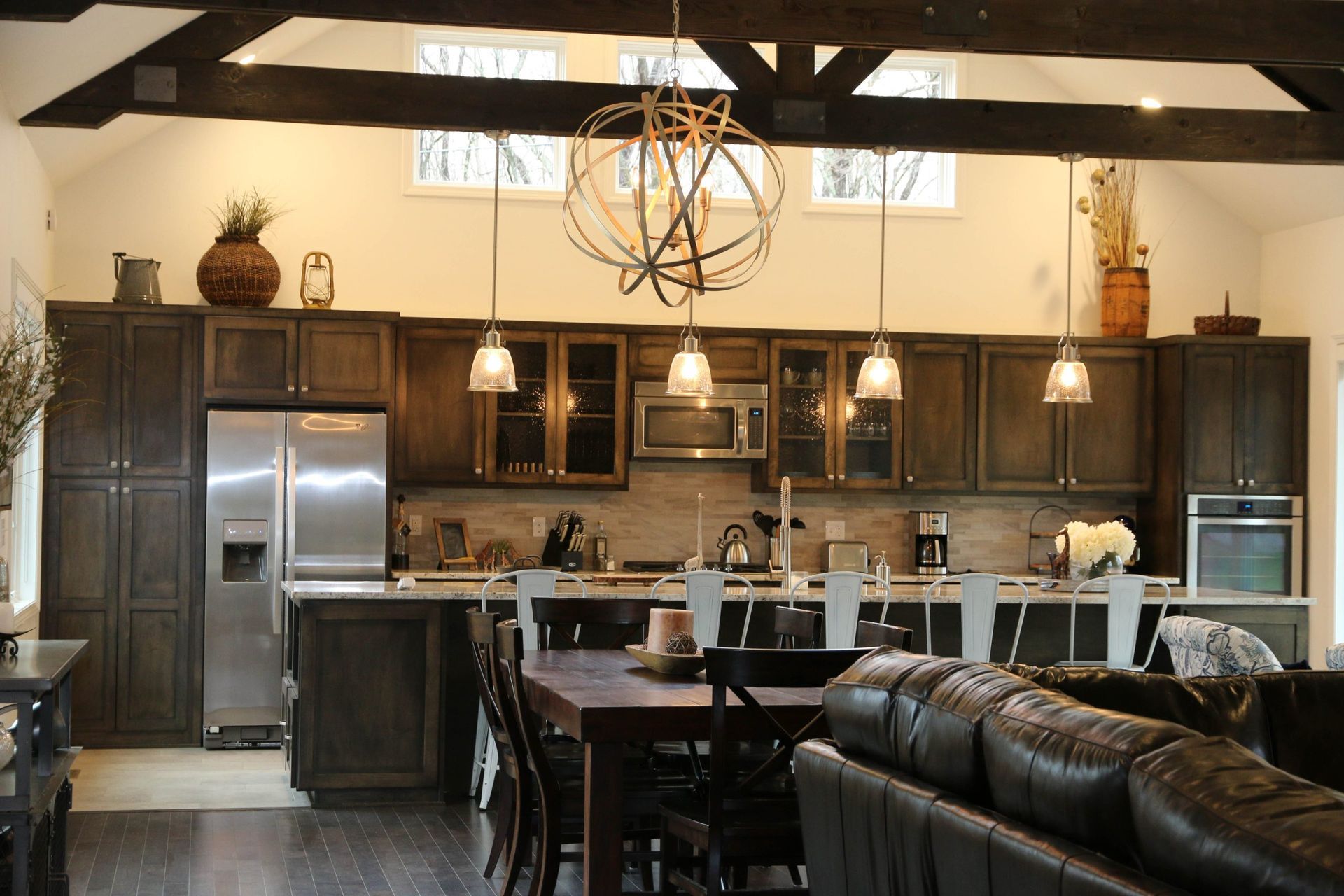 Spacious kitchen with dark wood cabinets, stainless steel appliances, a large center island, and exposed wood ceiling beams.