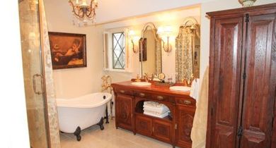 Elegant bathroom with a clawfoot tub, ornate vanity, and wood cabinet under warm lighting