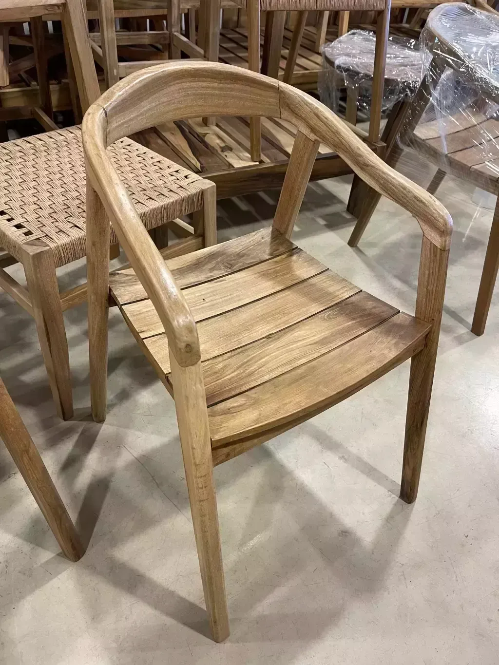Silla de madera con respaldo curvado y asiento de listones, en una habitación con otros muebles de madera.