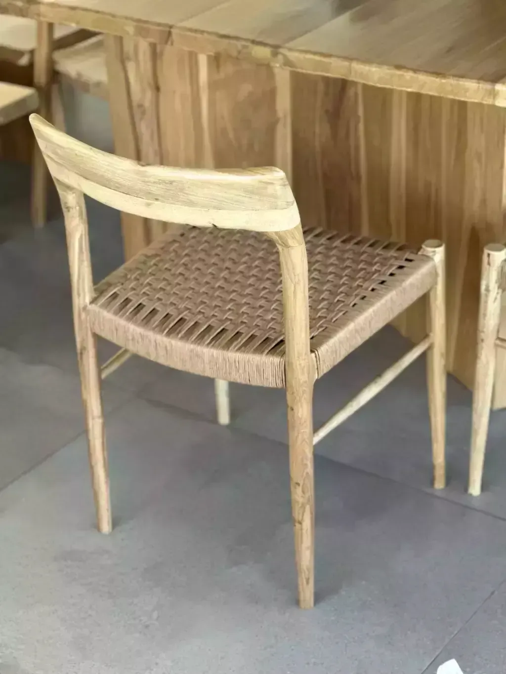 Dos sillas de madera clara con asientos tejidos, sobre un piso de baldosas.