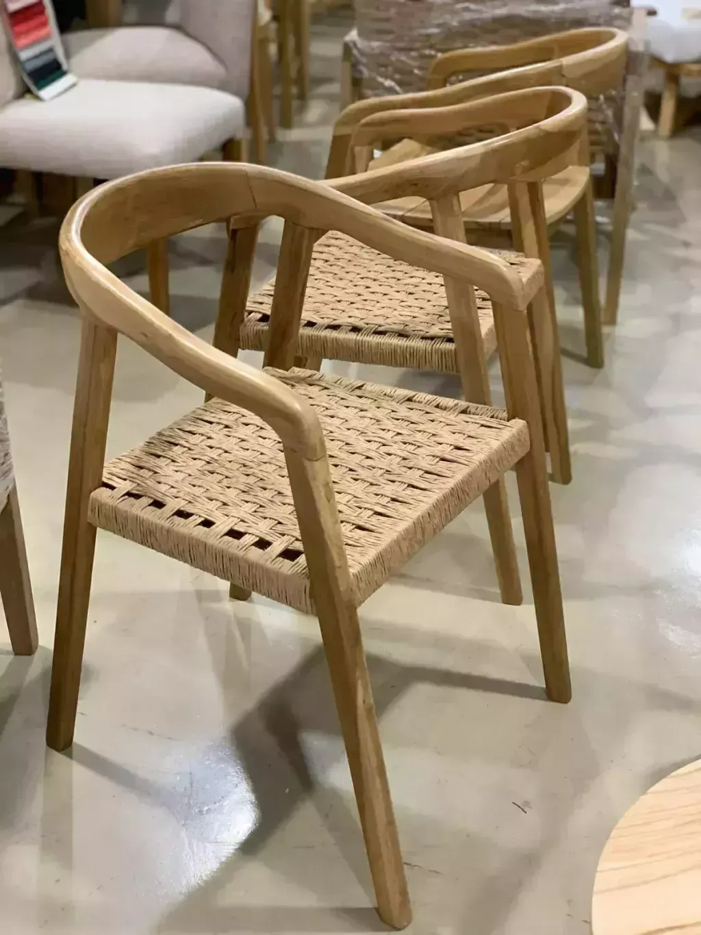 Sillas de madera con asientos tejidos, exhibidas en un entorno de sala de exposición.