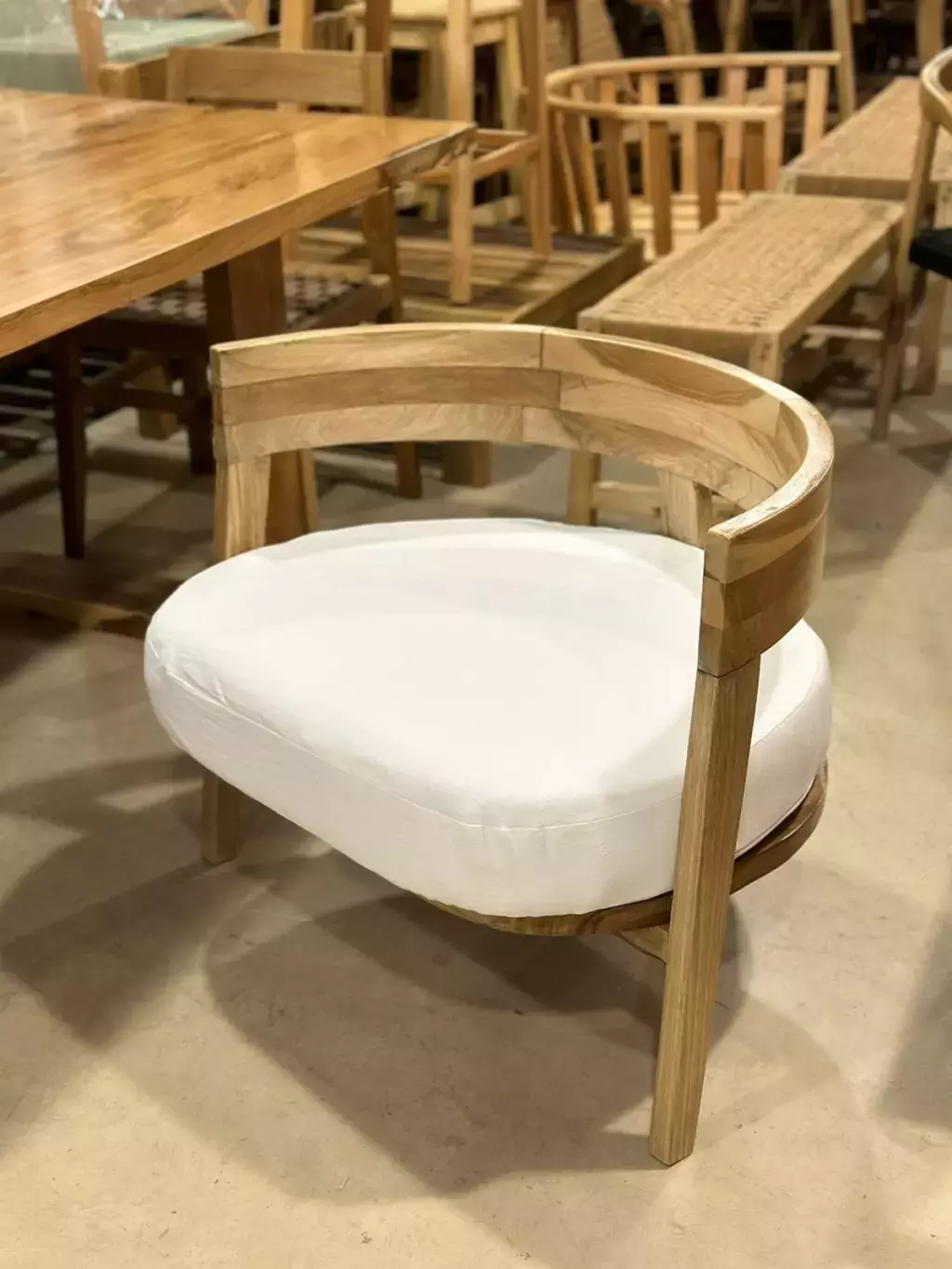 Silla de madera con respaldo curvado y cojín blanco en una habitación.