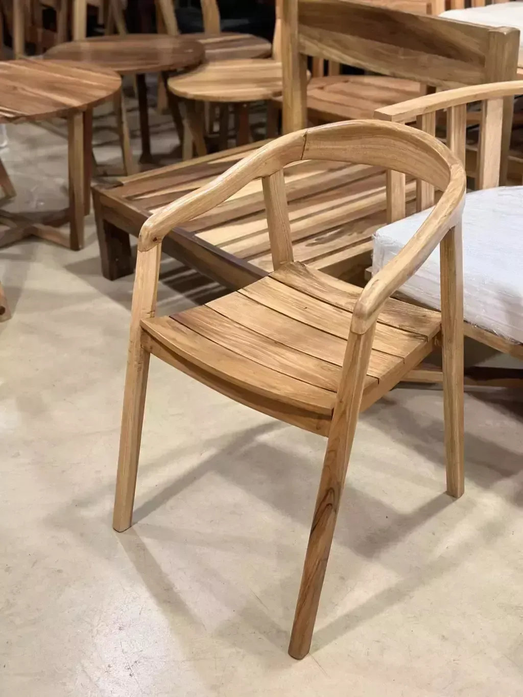 Silla de madera con respaldo curvado y asiento de listones, en una habitación con otros muebles de madera.