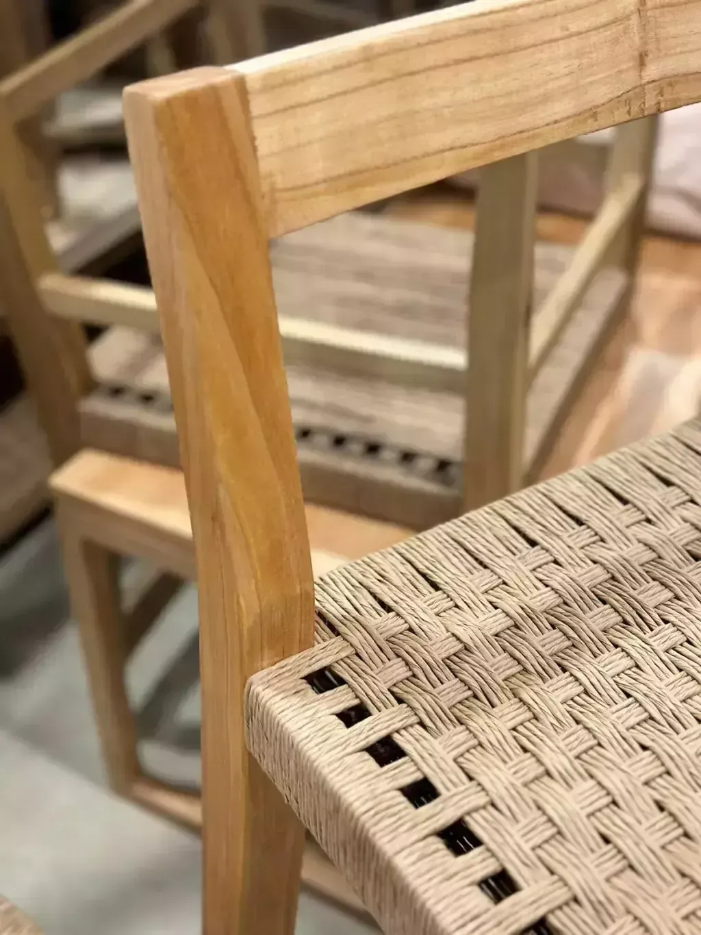 Taburete de bar de madera con asiento tejido, en un entorno de almacén.