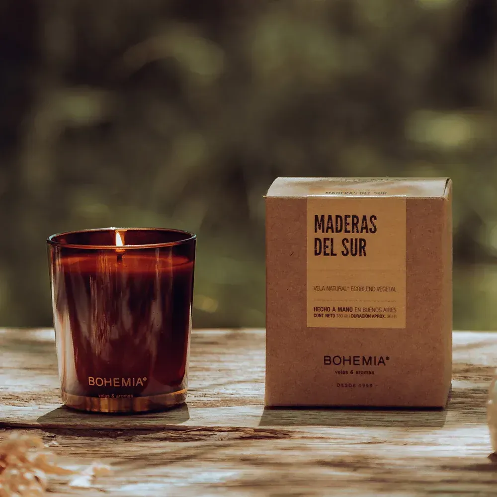 Vela encendida en vidrio marrón, junto a una caja marrón etiquetada 