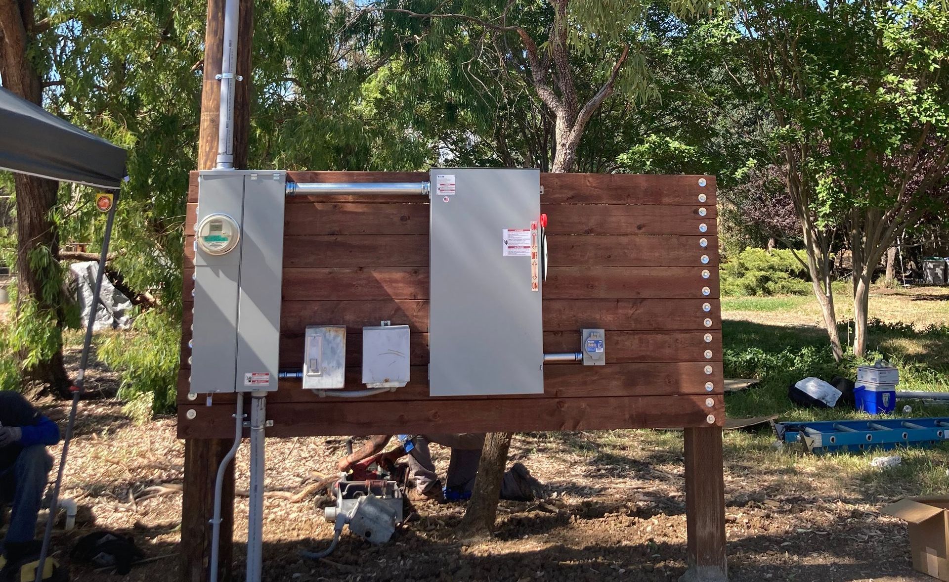 A wooden fence with electrical boxes attached to it.