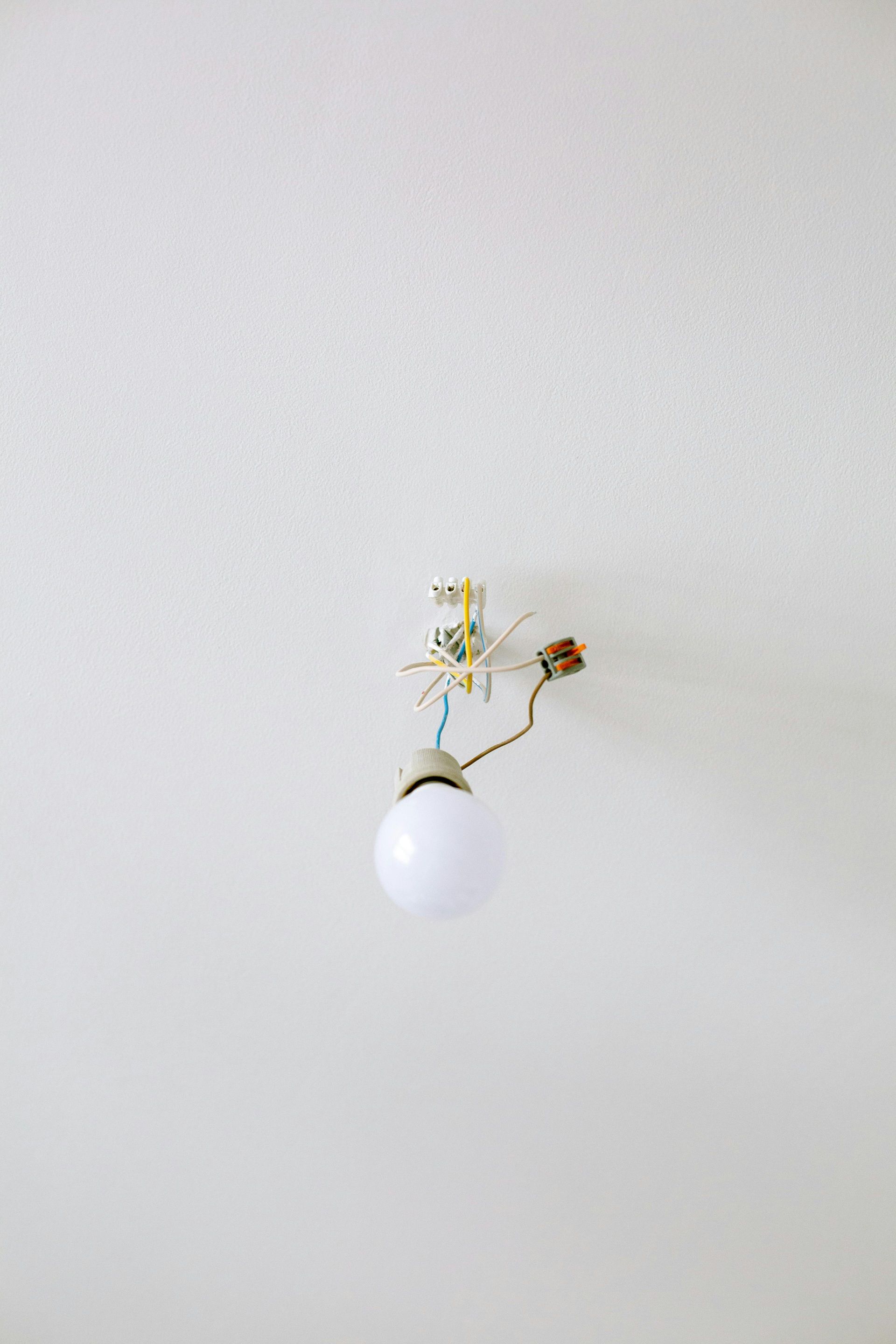 Electrician in hardhat installing electrical wiring.