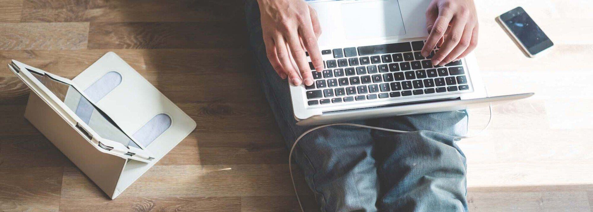 A person is sitting at a table using a laptop computer.