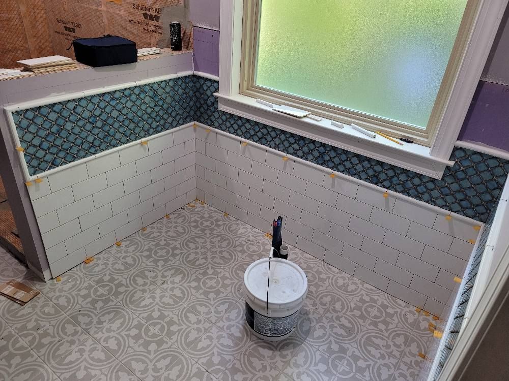 A bathroom with a bucket of paint and a window.