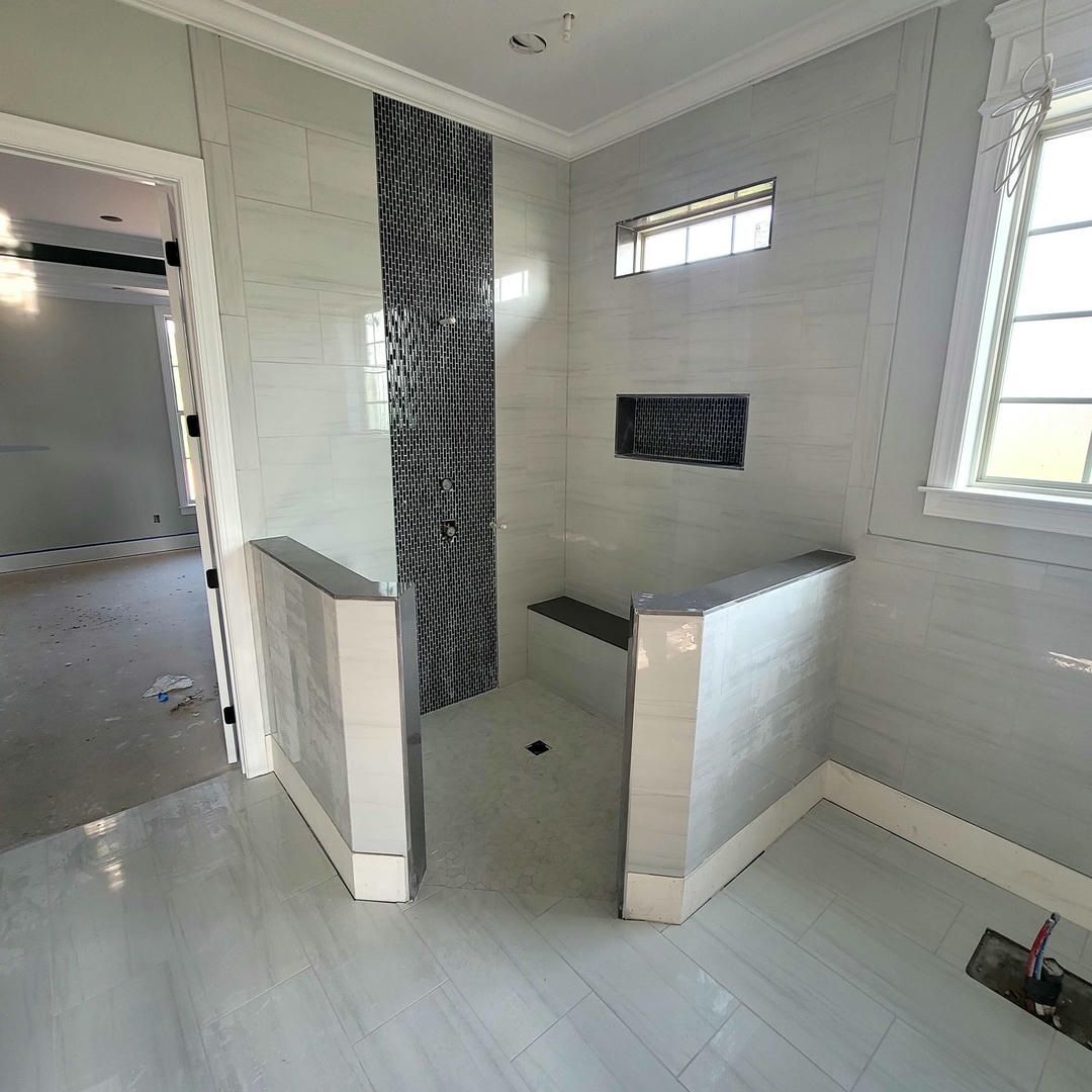 A bathroom with a walk in shower and a window.