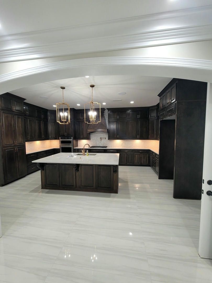 A kitchen with black cabinets and a large island in the middle