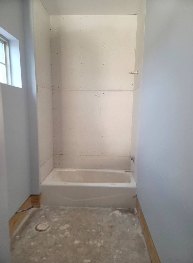 A bathroom with a bathtub and a window.