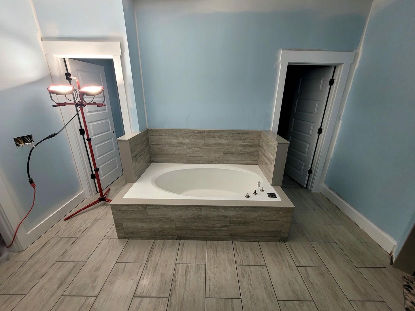 A bathroom with a bathtub and a light on the floor