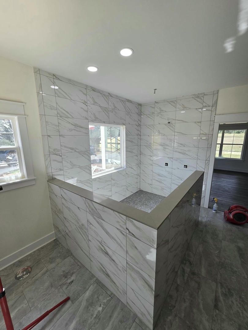 A bathroom with marble tiles and a window.