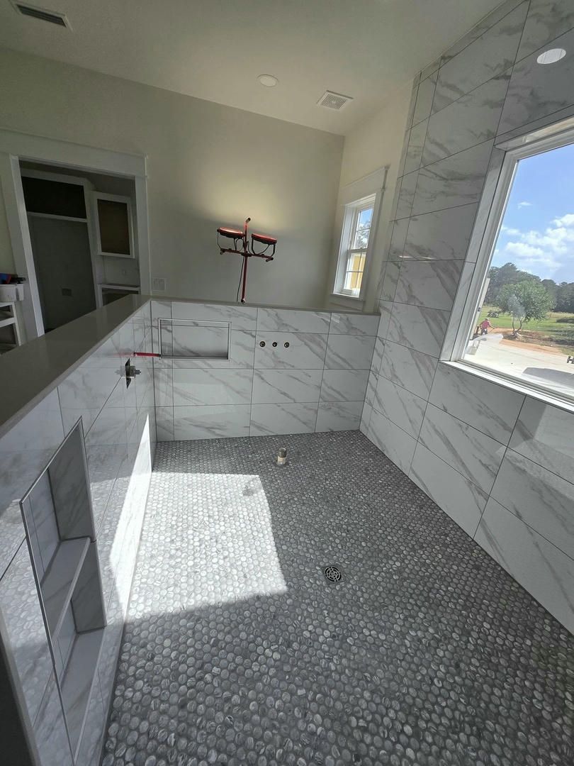 A bathroom with marble tiles and a walk in shower.