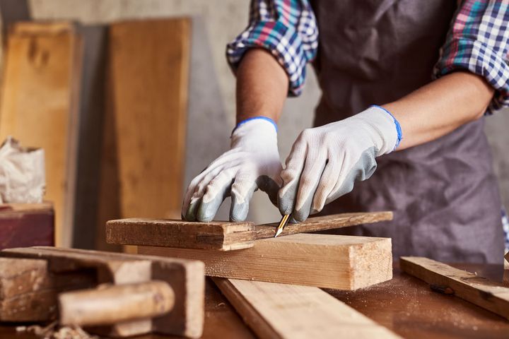 A person wearing gloves is cutting a piece of wood.