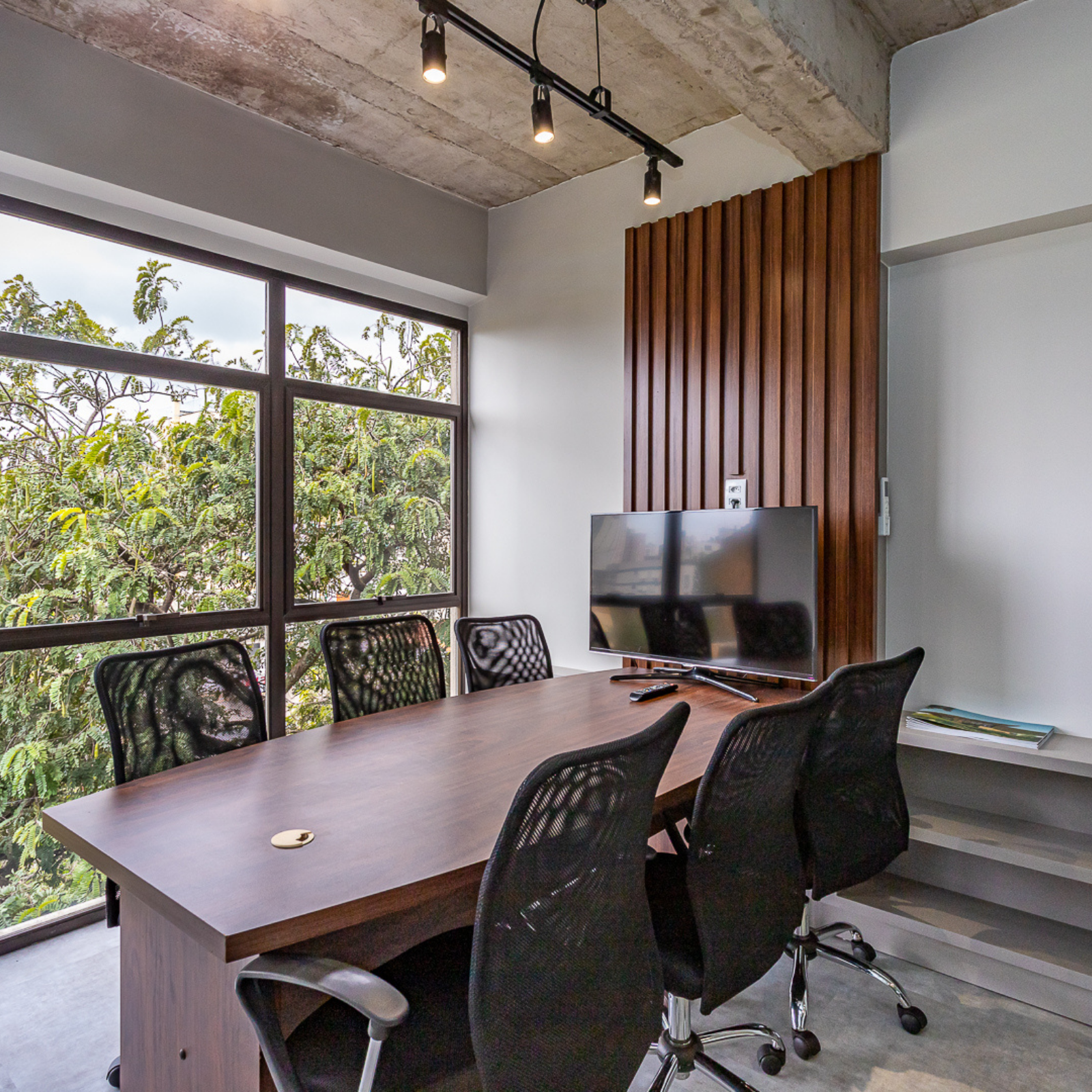 Uma sala de conferências com mesa e cadeiras e uma TV de tela plana.