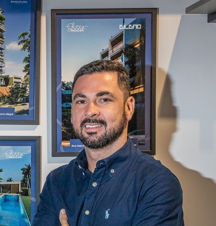 Um homem barbudo posa para uma foto com os braços cruzados