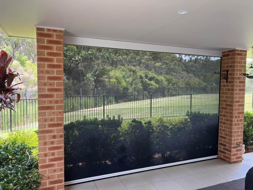 A Brick Wall With A Screen On It And A Fence In The Background — Outdoor Blinds In Cooranbong, NSW